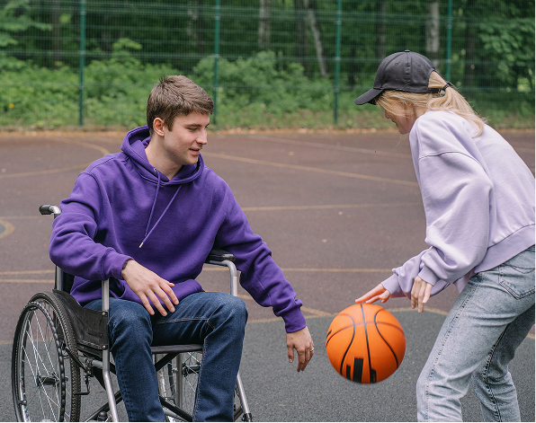 Person in wheelchair playing basketball with a friend