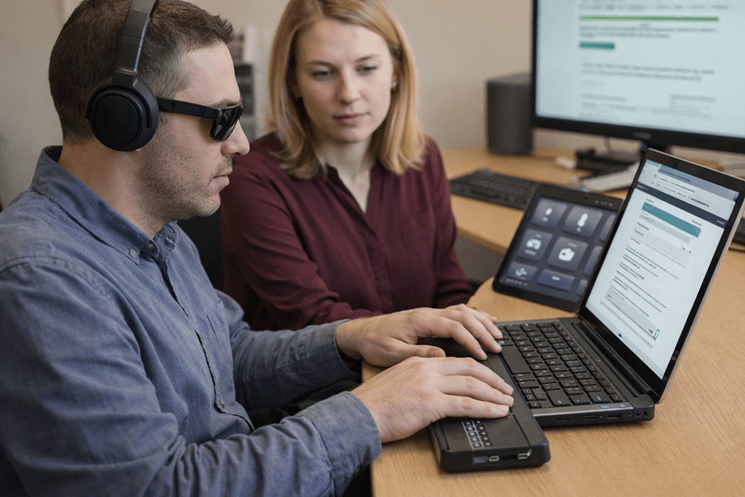 Accessibility testing in progress, showing a user with assistive technology and a reviewer evaluating website usability on a laptop.