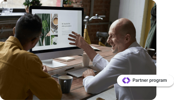 Two men sitting at a table, looking at a computer screen displaying a presentation, with one man smiling and gesturing. A button labeled 'Affiliate Program' is displayed in the bottom right corner.